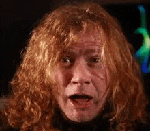 a man with long red hair is making a funny face .