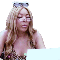 a woman wearing sunglasses and a leopard print top is sitting in front of a laptop .