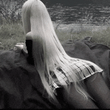 a woman with very long white hair is laying on a black blanket