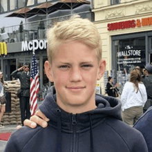 a young man in a hoodie is standing in front of a mcdonald 's restaurant .