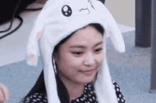 a woman wearing a white bunny hat with moving ears is smiling .