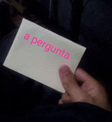 a person is holding a piece of paper that says " a pergunta "