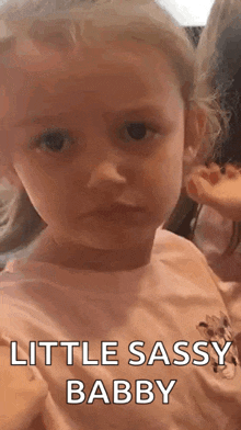 a little girl is making a funny face and says `` little sassy baby '' .