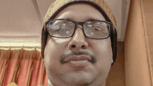 a man wearing glasses and a beanie has a mustache