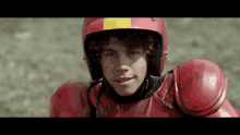 a young man wearing a red helmet with a yellow stripe on it