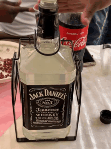 a bottle of jack daniel 's whiskey sits on a table next to a bottle of coca cola