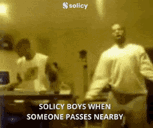 two men are dancing in front of a sign that says solicy boys when someone passes nearby