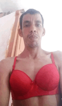 a man wearing a red bra is taking a selfie .