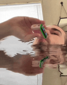 a man is holding a cell phone in his mouth while swimming in a bathtub