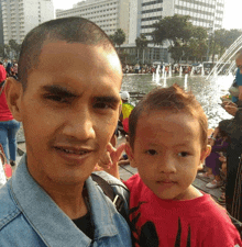 a man is holding a little boy in front of a fountain