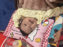 a baby is laying on a pillow that says hello kitty