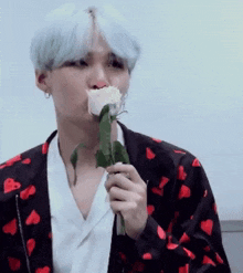 a man with white hair is holding a rose in his mouth .