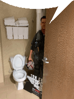 a man is standing in a bathroom with a sign that says tom cruise top gear maver