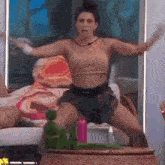 a woman in a crop top and shorts is dancing in front of a table .