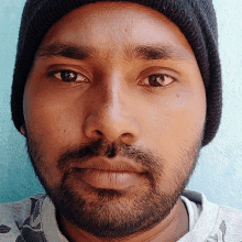 a man with a beard wearing a beanie looks at the camera