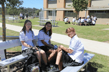 three girls sitting on a bench with a backpack that says santa cruz on it