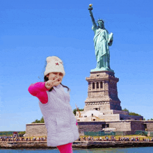 a little girl in front of the statue of liberty in new york city