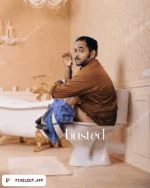 a man sits on a toilet in a bathroom with the word busted on the bottom right