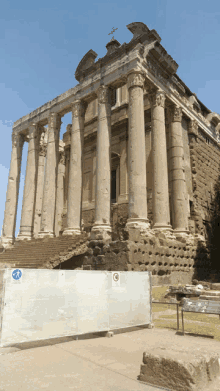 a building with columns and stairs has a fence around it