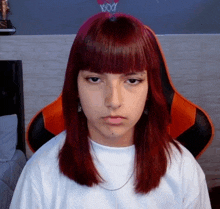 a girl with red hair is wearing a white t-shirt and an orange chair