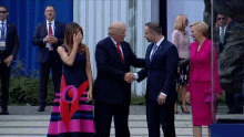 a woman in a pink dress is covering her face while a man in a suit shakes hands with donald trump