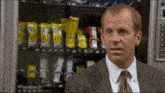 a man in a suit and tie stands in front of a vending machine that says 01 02 03 04