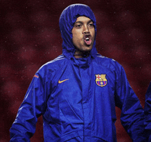 a man wearing a blue nike jacket with a fcb logo on the front