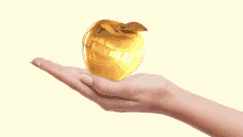 a woman 's hand is holding a gold apple