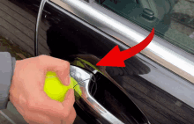 a person is holding a tennis ball in front of a car door handle