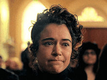 a woman with curly hair is making a funny face in front of a window .