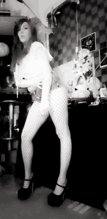 a black and white photo of a woman wearing fishnet stockings and heels