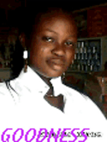 a woman wearing a white shirt and earrings is standing in front of a refrigerator .