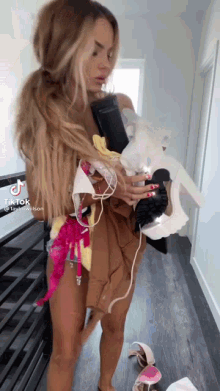 a woman without a shirt is holding a pile of clothes and shoes .