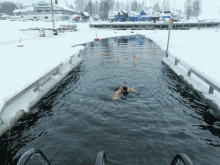 a person is swimming in a body of water that is surrounded by snow