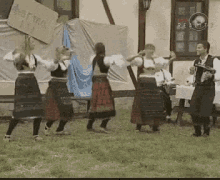 a group of people are dancing in a field in front of a building with a sign that says real estate on it