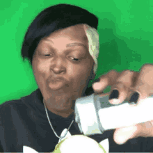 a woman is making a funny face while holding a bottle in front of her face .