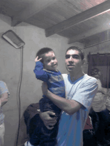 a man in a blue shirt is holding a little boy in his arms