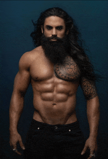 a shirtless man with long hair and a beard has a tattoo on his arm