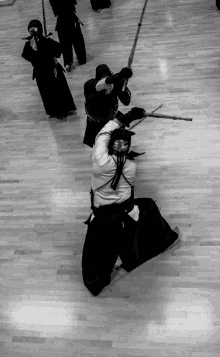 a black and white photo of people practicing martial arts on a wood floor