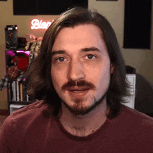 a man with long hair and a beard stands in front of a sign that says blog