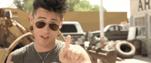 a young man wearing sunglasses is giving a thumbs up sign .