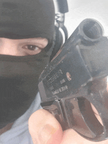 a man wearing a black mask is holding a gun that says made in germany on the side