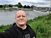 a man taking a selfie with a bridge in the background wearing a shirt that says l' hino