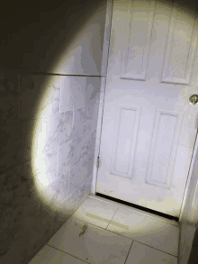 a door with a light shining on it and a marble wall