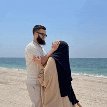 a man and a woman are standing on a beach looking at each other