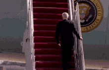 a man in a suit climbs the stairs of an airplane with the seal of the united states on the side