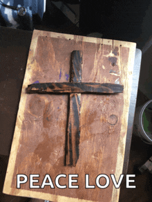 a wooden cross on a wooden board with the words peace love