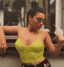 a woman in a neon green tank top is holding a drink