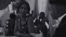 a black and white photo of a man and a woman sitting at a table .