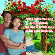 a man and a woman are posing for a picture in front of a floral archway